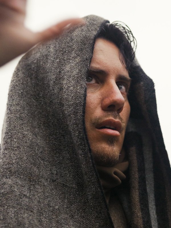 Matías De Stefano wrapped in a dark blanket.